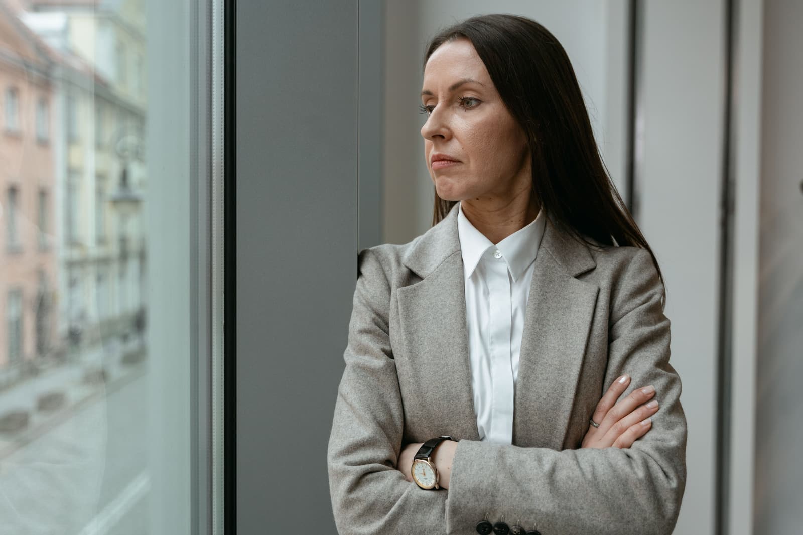 A woman standing with her arms folded, thinking.