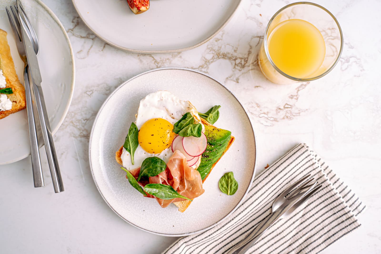 Poached egg, greens and juice on a marble table.