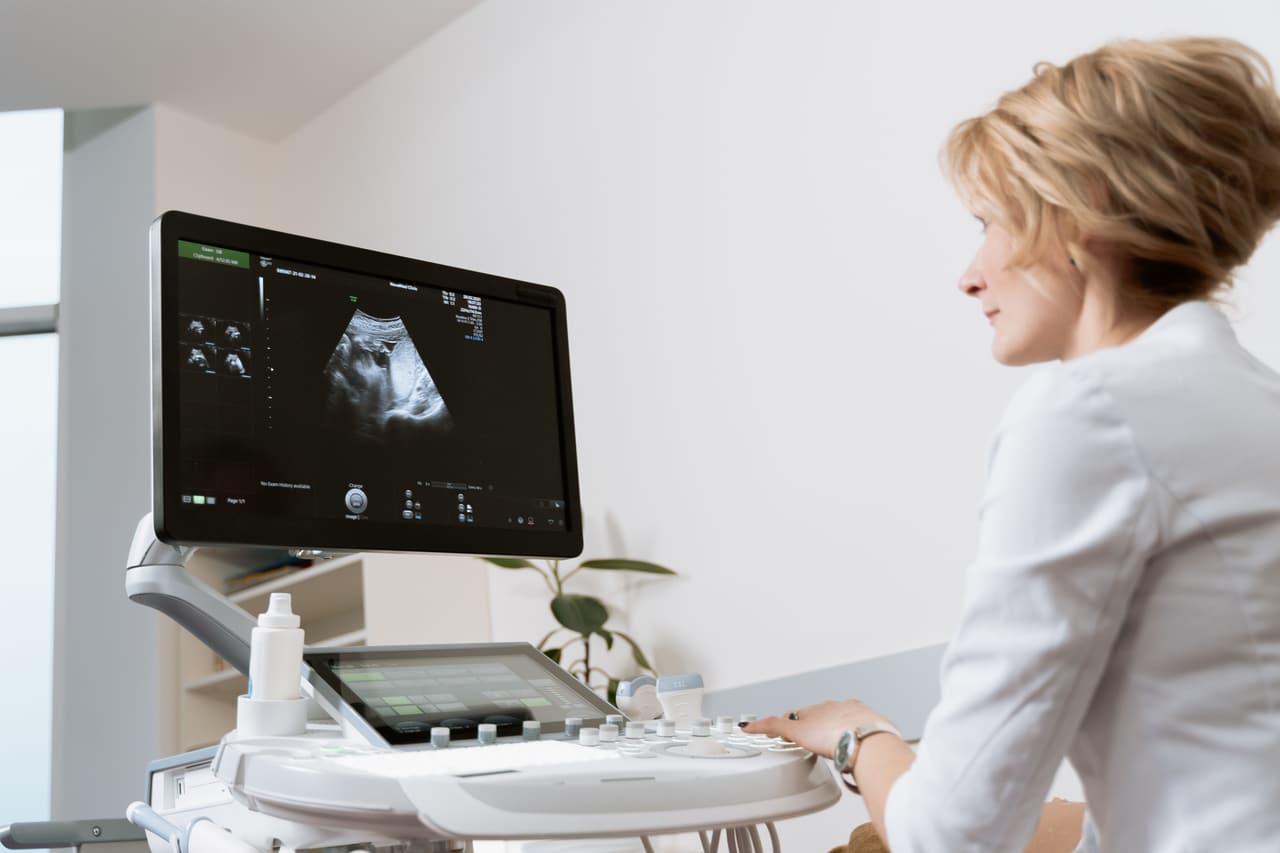 A clinician at an ultrasound console with the scan on screen.